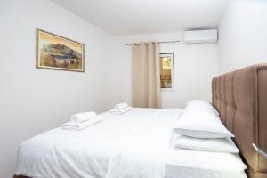 a bedroom with a white bed with white sheets at Apartments Natasa in Sveti Stefan
