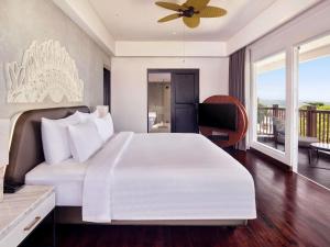 a bedroom with a large white bed and a balcony at Grand Mercure Bali Seminyak in Seminyak