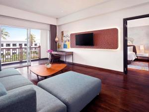 a living room with a couch and a tv at Grand Mercure Bali Seminyak in Seminyak