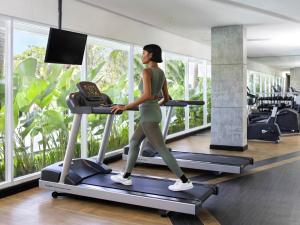 a woman running on a treadmill in a gym at Grand Mercure Bali Seminyak in Seminyak