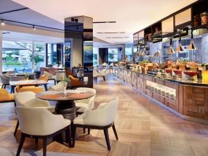 a restaurant with tables and chairs and a bar at Grand Mercure Bali Seminyak in Seminyak