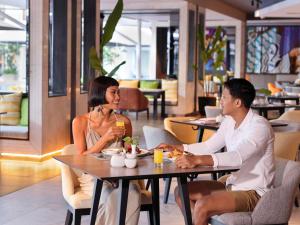 a man and woman sitting at a table in a restaurant at Grand Mercure Bali Seminyak in Seminyak