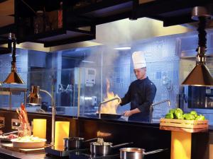 a chef preparing food in a restaurant kitchen at Grand Mercure Bali Seminyak in Seminyak