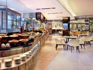 a restaurant with a buffet with tables and chairs at Grand Mercure Bali Seminyak in Seminyak