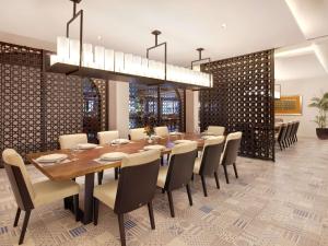a dining room with a large wooden table and chairs at Grand Mercure Bali Seminyak in Seminyak