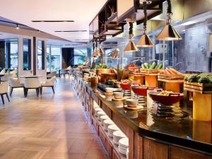 a restaurant with a buffet line with bowls of food at Grand Mercure Bali Seminyak in Seminyak