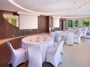 a room with white tables and white chairs and a screen at Grand Mercure Bali Seminyak in Seminyak