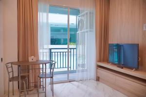 a room with a television and a table and a balcony at D Eco Wellness Center in Pattaya North