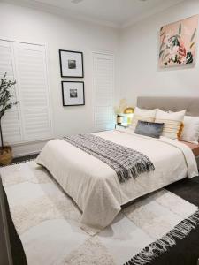 a bedroom with a large white bed with a rug at Modern Luxe Retreat Brisbane in Doolandella
