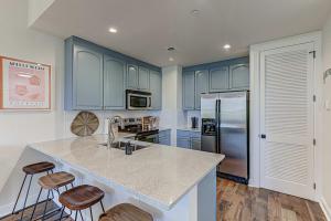 a kitchen with blue cabinets and a kitchen island with stools at Waterfront Condo for 4 with Resort Pool & Lake View in Horseshoe Bay