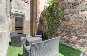 patio z wiklinowymi krzesłami i ceglaną ścianą w obiekcie Forêt Urbaine - Jolie T3 avec terrasse w mieście Montluçon