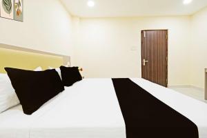 a bedroom with a large white bed with black pillows at Hotel O Sanath Nagar Near Railway Station in Hyderabad