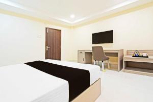a bedroom with a bed and a desk with a television at Hotel O Sanath Nagar Near Railway Station in Hyderabad