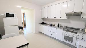 Una cocina blanca con gabinetes blancos y una estufa. horno superior en CASA do CAMPO Lestrove, en Padrón