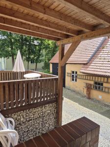 NiederdorlaにあるHaus am Wendseeの木製のフェンスと建物のある屋外デッキ +1枚の写真