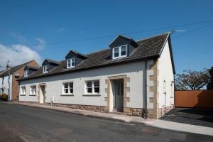 een wit huis aan de kant van een straat bij Wall Cottage in Coldstream