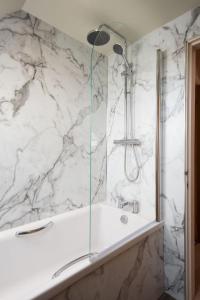 een douche in een badkamer met een witte marmeren muur bij Wall Cottage in Coldstream +13 foto's