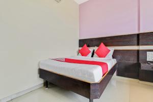 a bedroom with a bed with red pillows at Hotel O Sai Kohinoor in Shirdi