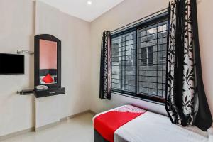 a bedroom with a window and a bed and a mirror at Hotel O Sai Kohinoor in Shirdi