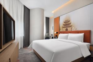 una camera da letto con un grande letto bianco e una televisione di Hampton by Hilton Nanjing Xianlin University Town a Nanjing