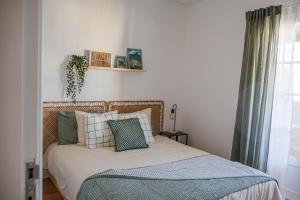 a bedroom with a bed with pillows and a window at House Pachamama in Olhão