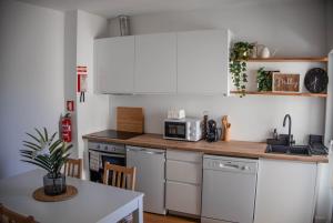 a kitchen with white cabinets and a table with a microwave at House Pachamama in Olhão +10 photos