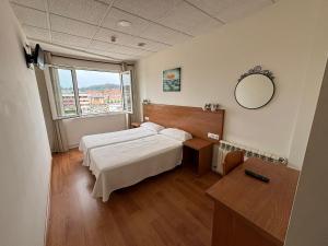 a hotel room with two beds and a mirror at Hotel Besaya in Torrelavega