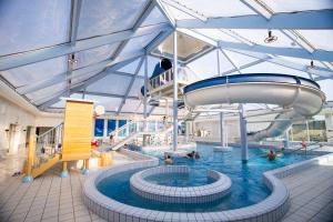 a indoor pool with a slide and people in the water at Best Western Plus Hotel Fredericia in Fredericia