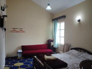コダイカナルにあるKodai Queen Homestayのベッドと赤いソファのある寝室