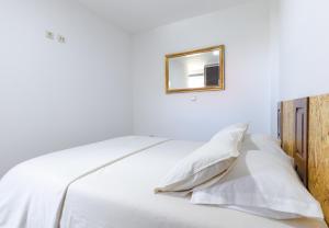 ein weißes Bett mit weißen Kissen und einem Bild an der Wand in der Unterkunft House Dinavast Bungalow in São João da Pesqueira