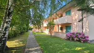 un edificio con fiori rosa accanto a un marciapiede di APARTMENT ORTENSIA - Regarda Travel a Lazise