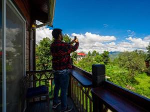 アルモラにあるThe Hosteller Kasar Deviのバルコニーに立って景色の写真を撮っている男性