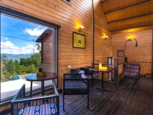 a room with tables and chairs and a large window at The Hosteller Kasar Devi in Almora
