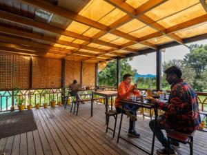 two men sitting at tables on the deck of a restaurant at The Hosteller Kasar Devi in Almora