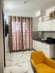 a kitchen with curtains and a yellow chair in a room at Fully Furnished Flat WTC 106 in Gurgaon