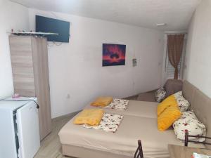 a small room with a bed with yellow pillows on it at APARTMANI MARIJA in Čanj