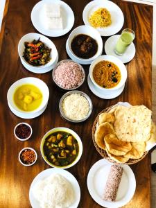a wooden table with plates of different types of food at Royal Lion Hotel - Kandy Road, Galagadara in Galagedara