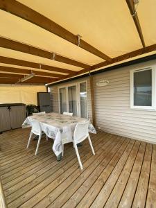 Un patio con una mesa y sillas en una terraza. en Mobile home à Mimizan, en Mimizan