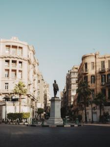 a statue in the middle of a city with buildings at Brassbell l DT l Hannaux l Tahrir sq in Cairo