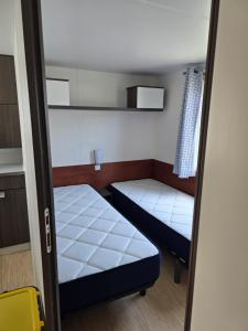 a small room with two beds and a window at Mobile home à Mimizan in Mimizan +2 photos