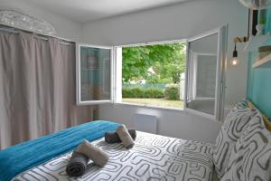 a bedroom with a bed and a large window at Sous le Marronnier - Maison pour 4 avec jardin in Royan