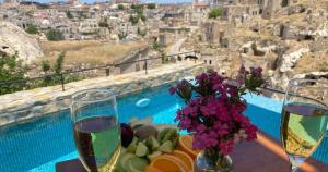 a table with two glasses of wine and a plate of food at Portal Cappadocia - Adults Only Cave Hotel in Ortahisar