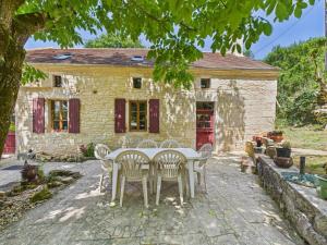 BorrèzeSalignac-Eyvigues, maison pour 7 avec piscine的石头房子前面的一张桌子和椅子