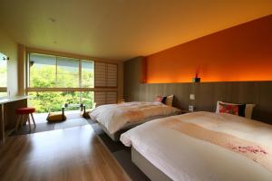 zwei Betten in einem Schlafzimmer mit einer orangefarbenen Wand in der Unterkunft Hotel Miyama in Chichibu + 27 Fotos
