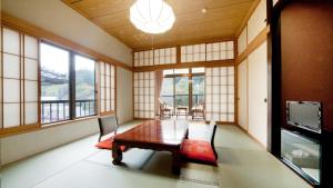 una sala da pranzo con tavolo, sedie e finestre di Ayameya Ryokan a Nakanojo