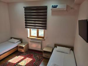 a small room with two beds and a window at Donish Hotel in Bukhara