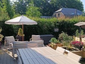 a patio with a table and an umbrella and chairs at Auprès de mon arbre in Gros-Fays