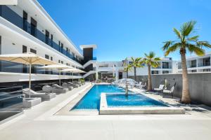 an outdoor pool with chairs and palm trees in front of a building at Bareti Boutique Estate in Kallithea Halkidikis