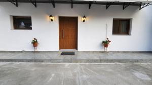 a white building with a wooden door and two potted plants at DGK way in Troulos