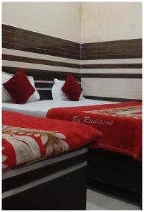 2 letti con cuscini rossi e bianchi in una stanza di VRINDAVAN HOTEL GAYATRI DHAM PALACE Near Temple - Fully Air Conditioned Hotel - Wi-fi #Free Parking #Room Service - A Premium Hotel At Best Location a Vrindāvan